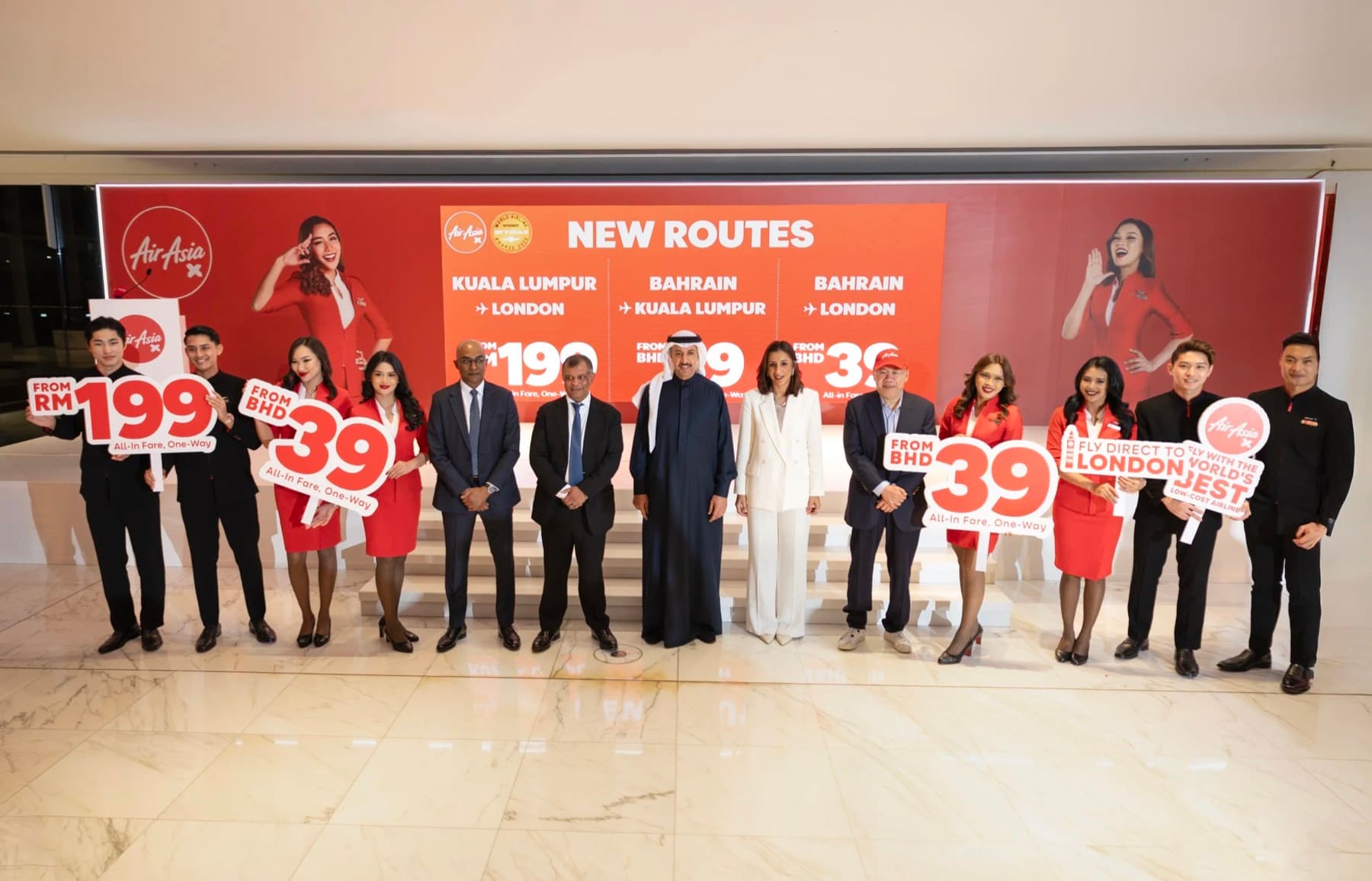 AirAsia X executives and Bahrain officials at a route-launch event in front of a NEW ROUTES backdrop listing Kuala Lumpur–London and Bahrain fares