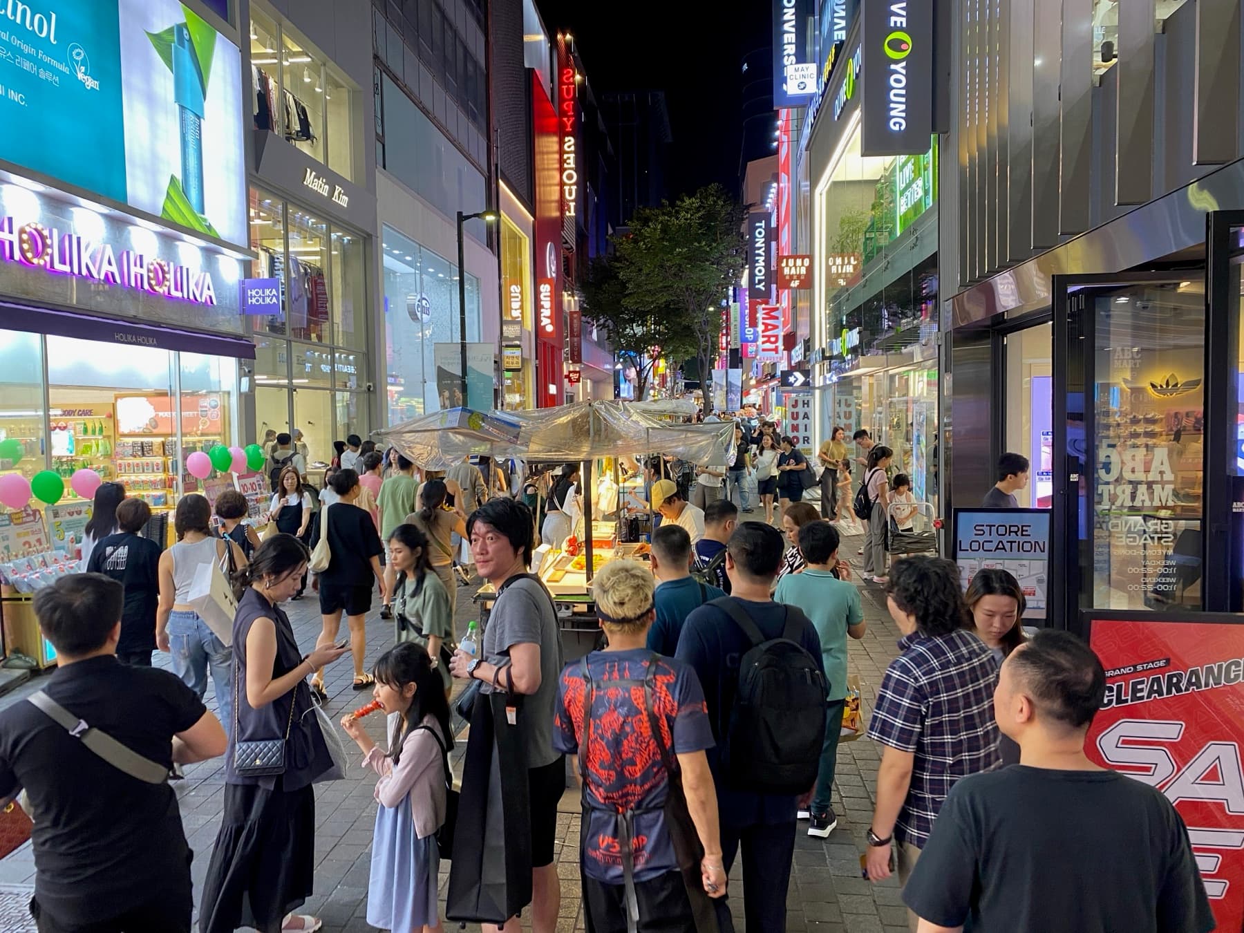Night crowds and neon storefronts in Seoul’s Myeongdong district, the foot traffic that underwrites nearby hotel values