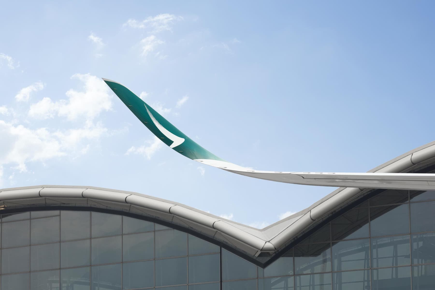 Cathay Pacific Airbus A350 winglet with brushwing logo over Hong Kong International Airport — Cathay Pacific Just Posted Its Best First-Half Profit Since 2010. What Does That Mean for Transpacific Travelers?