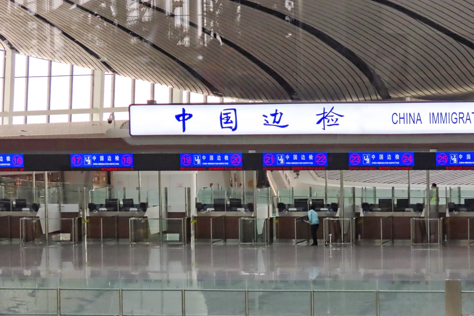 China Immigration Inspection counters numbered 16 to 25 under a bilingual CHINA IMMIGRATION sign at Beijing Daxing International Airport — China’s New Five-Year Entry Ban Makes Visa “Shortcuts” a Much Bigger Risk