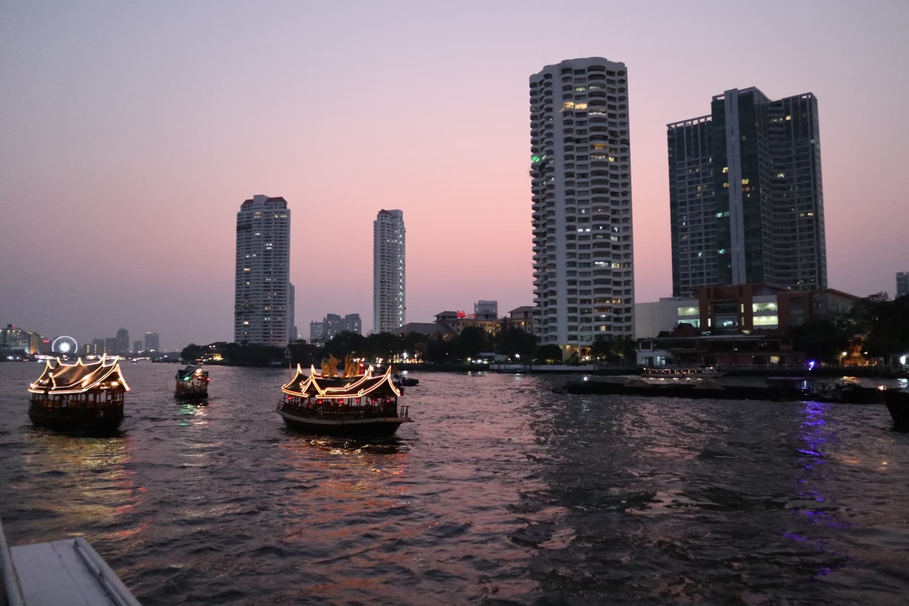 Evening boats and city lights along Bangkok’s Chao Phraya River after sunset