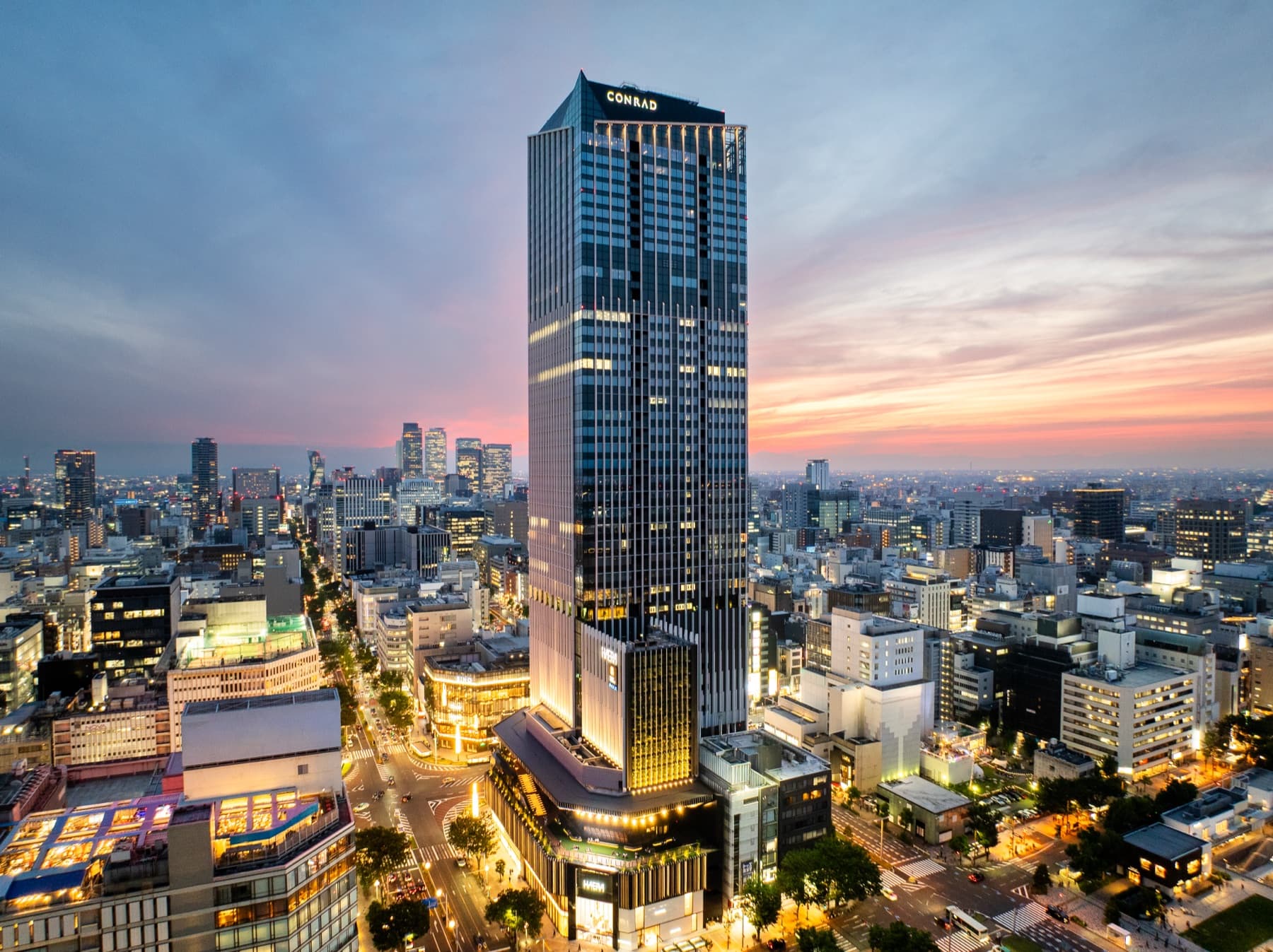 The Landmark Nagoya Sakae tower with the illuminated Conrad name rising above central Nagoya at sunset