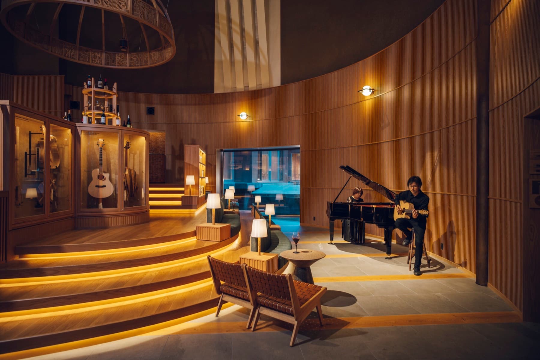 Circular wood-paneled lobby at KAI Matsumoto with Nagano wine bar seating and musicians at piano and guitar during the evening Sonority Concert — KAI Matsumoto Reopened With Italian Dinner, Nagano Wine, and a Nightly Lobby Concert