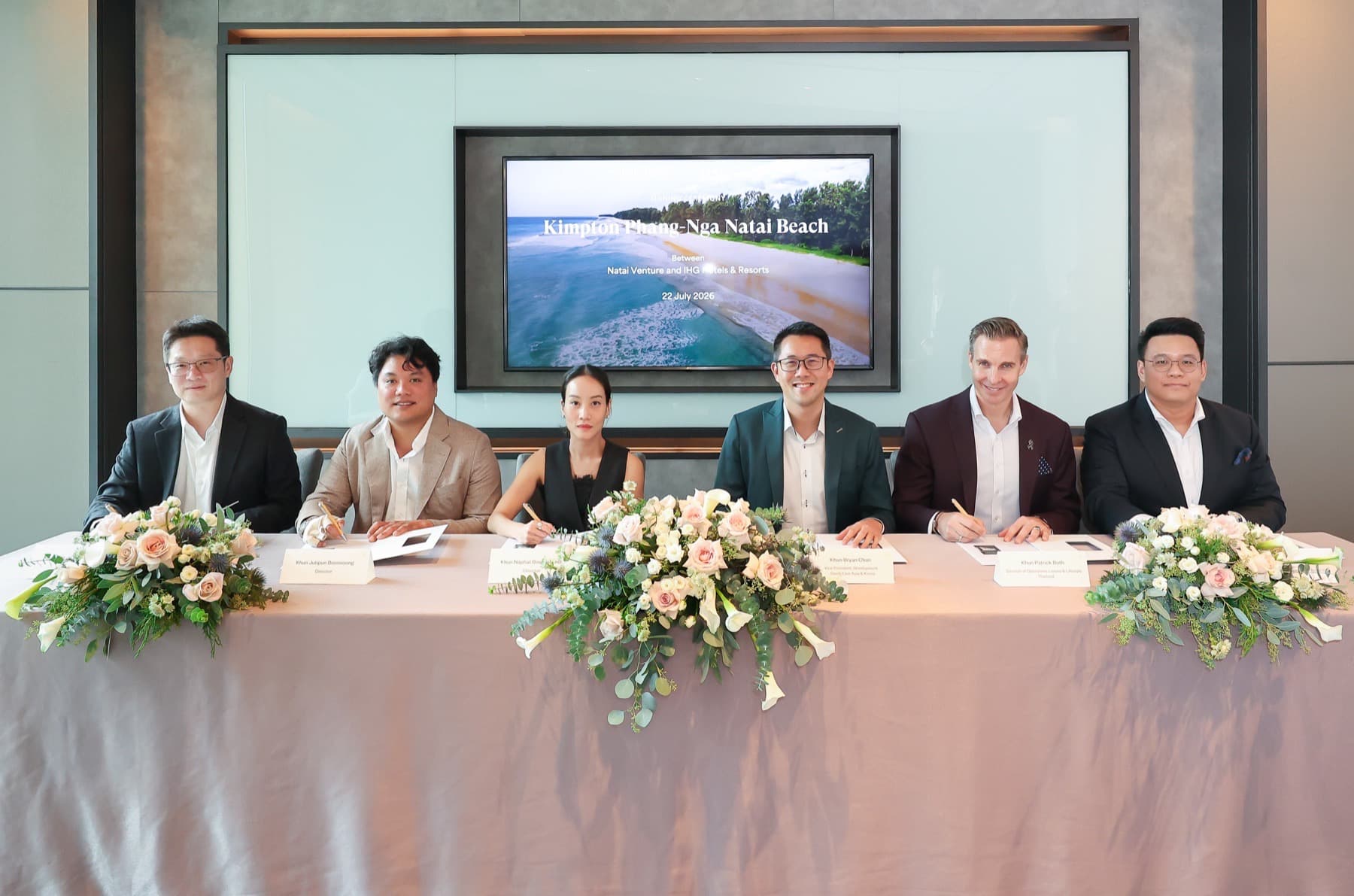 IHG and Natai Venture executives at the Kimpton Phang-Nga Natai Beach signing ceremony, with a Natai coastline image on the backdrop screen