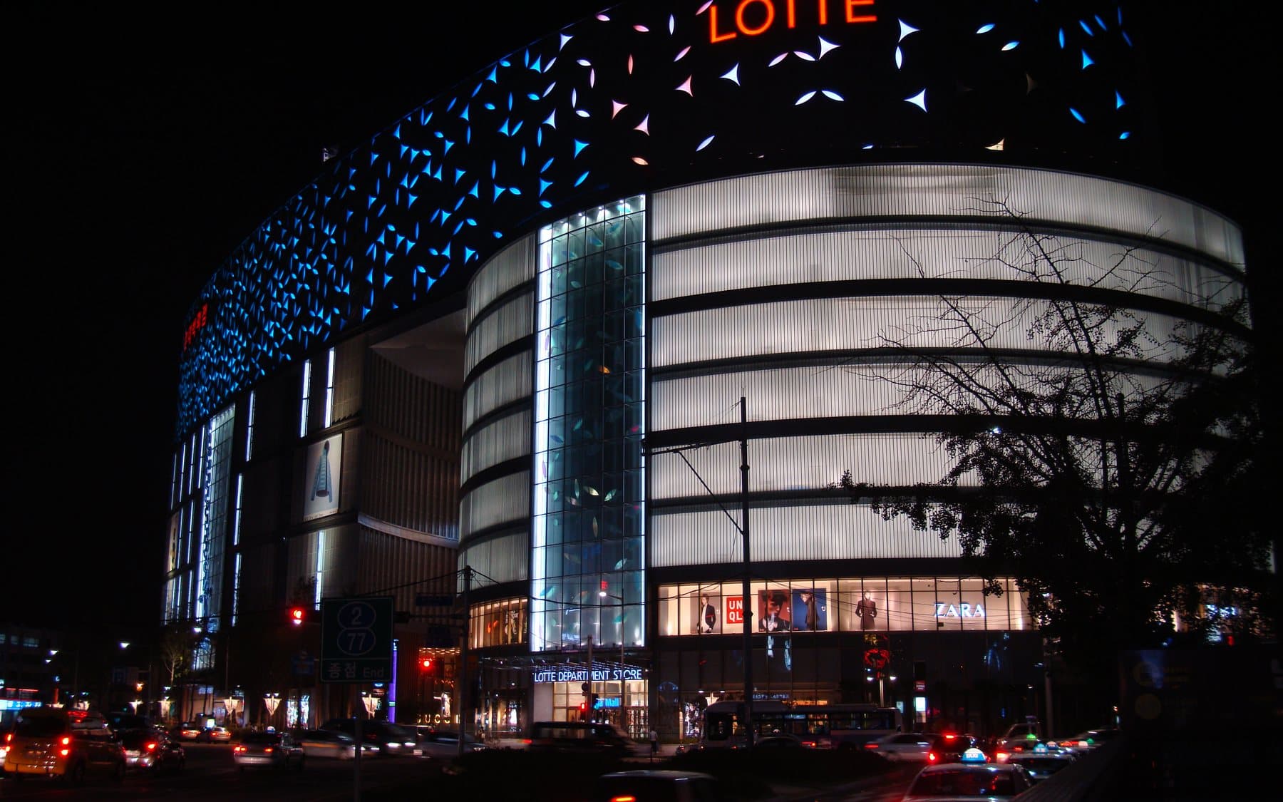 The curved, brightly lit Lotte Department Store in Busan at night, with traffic in front