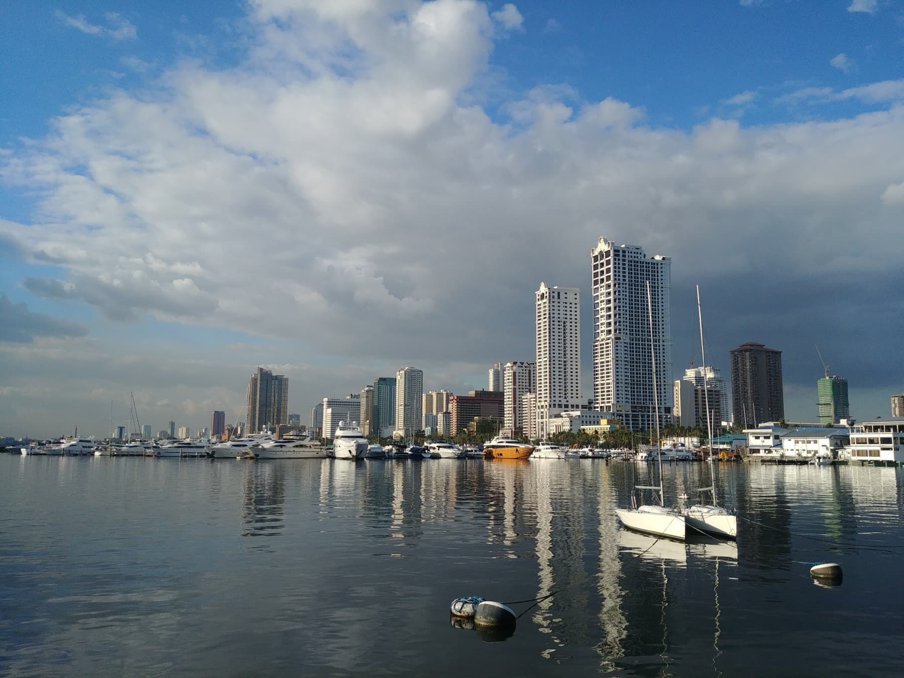 Manila Bay skyline and yacht marina under a cloudy sky