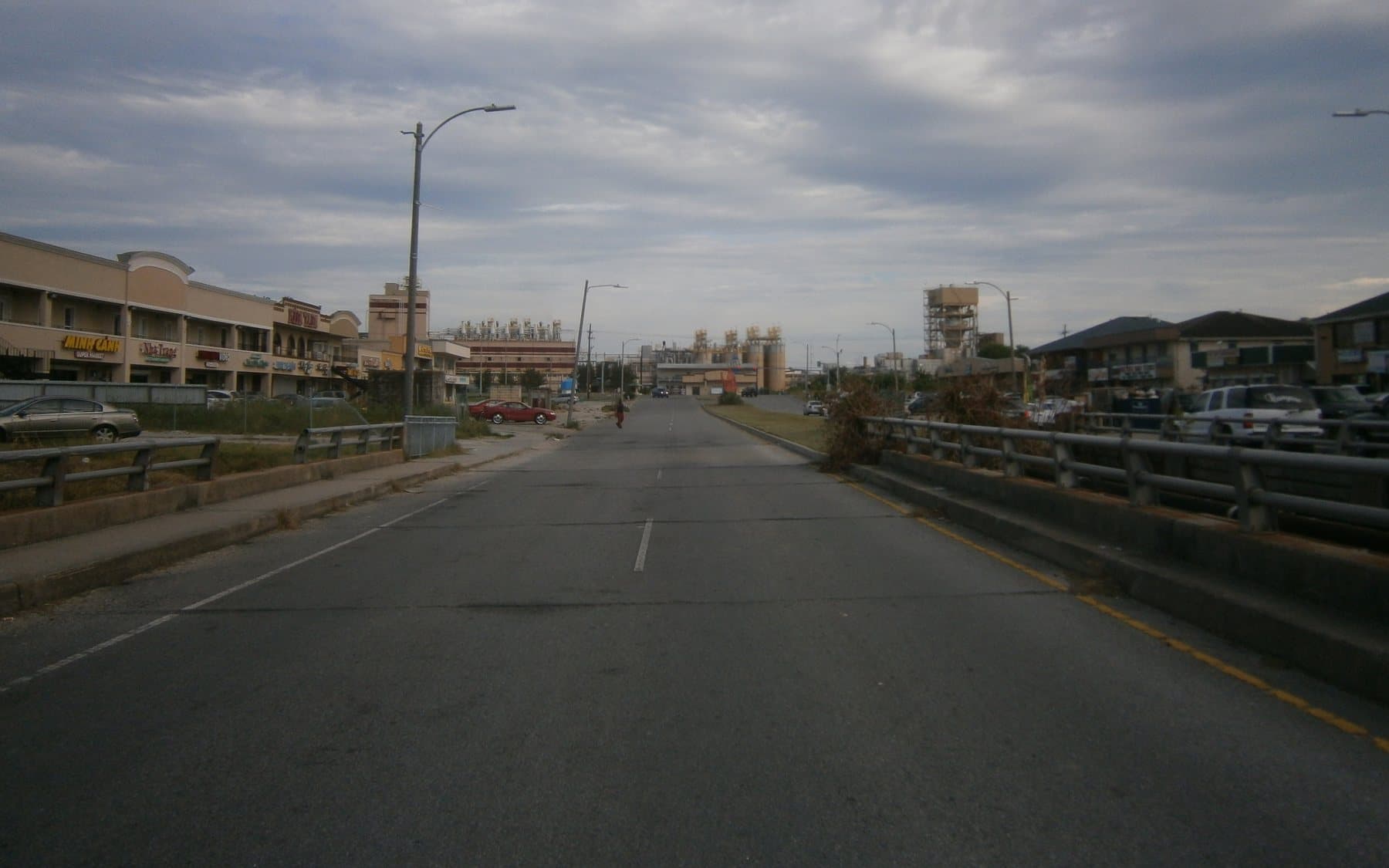 A commercial strip and grain elevators along a wide road in Village de l’Est, New Orleans East