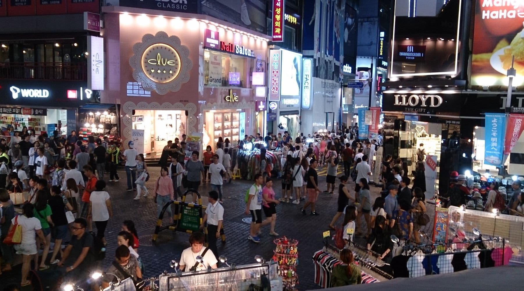 Crowded Myeongdong shopping street in Seoul at night under dense Hangul and English neon signs — Seoul Approaches 102°F as South Korea Mobilizes Against an Extreme Heatwave