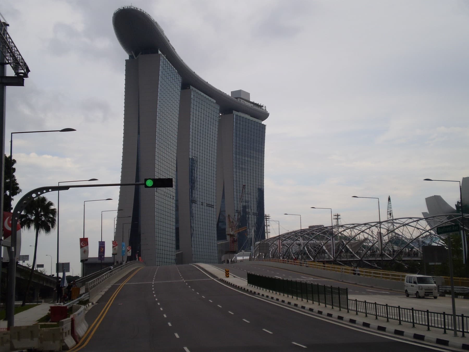 Marina Bay Sands and the Helix Bridge with Singapore flags along the roadside