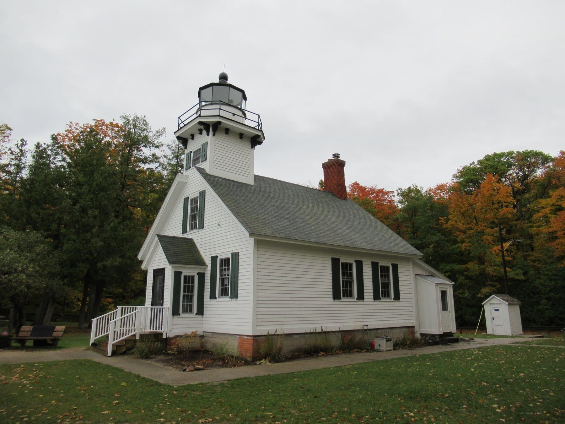 Mission Point Light, a white clapboard lighthouse with fall color behind it, on Old Mission Peninsula