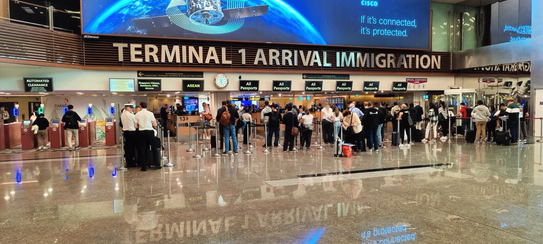 Travelers with suitcases queued beneath a Terminal 1 Arrival Immigration sign at Singapore Changi Airport, facing passport counters and automated clearance lanes — U.S. Visa Rules Are Tightening Just as Asian Travel Demand Accelerates