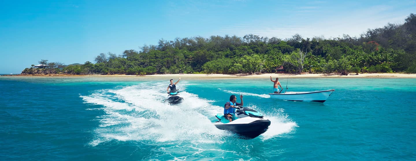 Jet skis and boat on turquoise water off a Fijian beach
