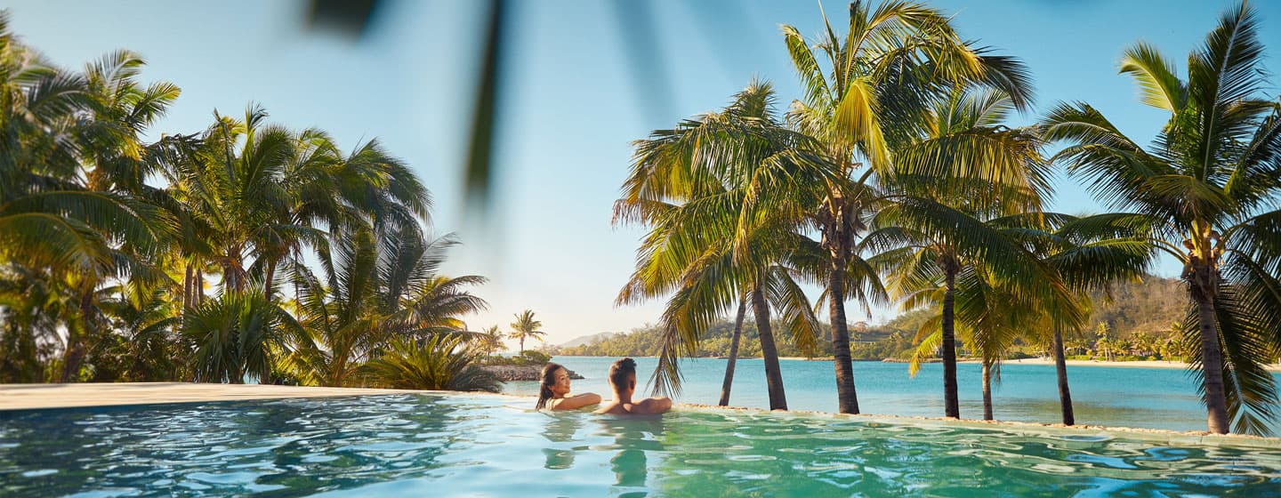 Couple at an infinity pool overlooking a Fijian lagoon